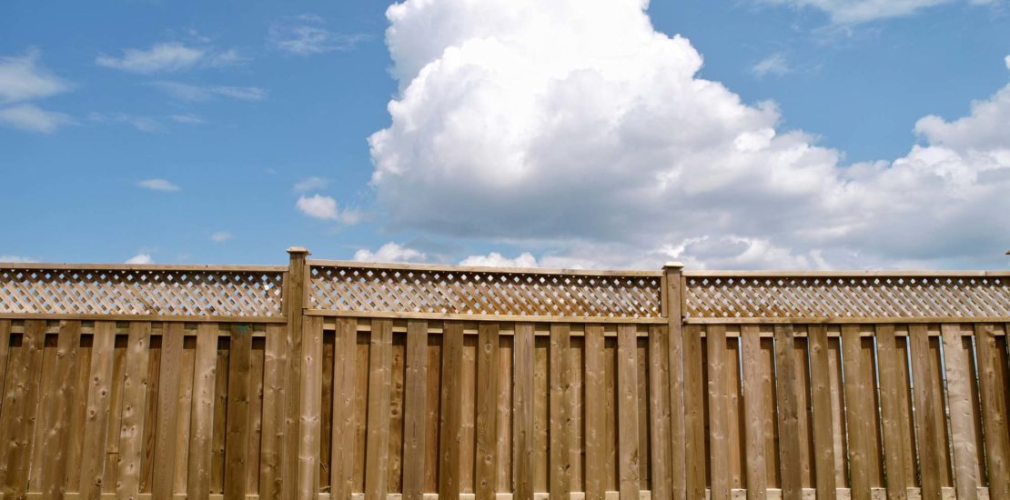 Wooden fence under cloudy blue sky