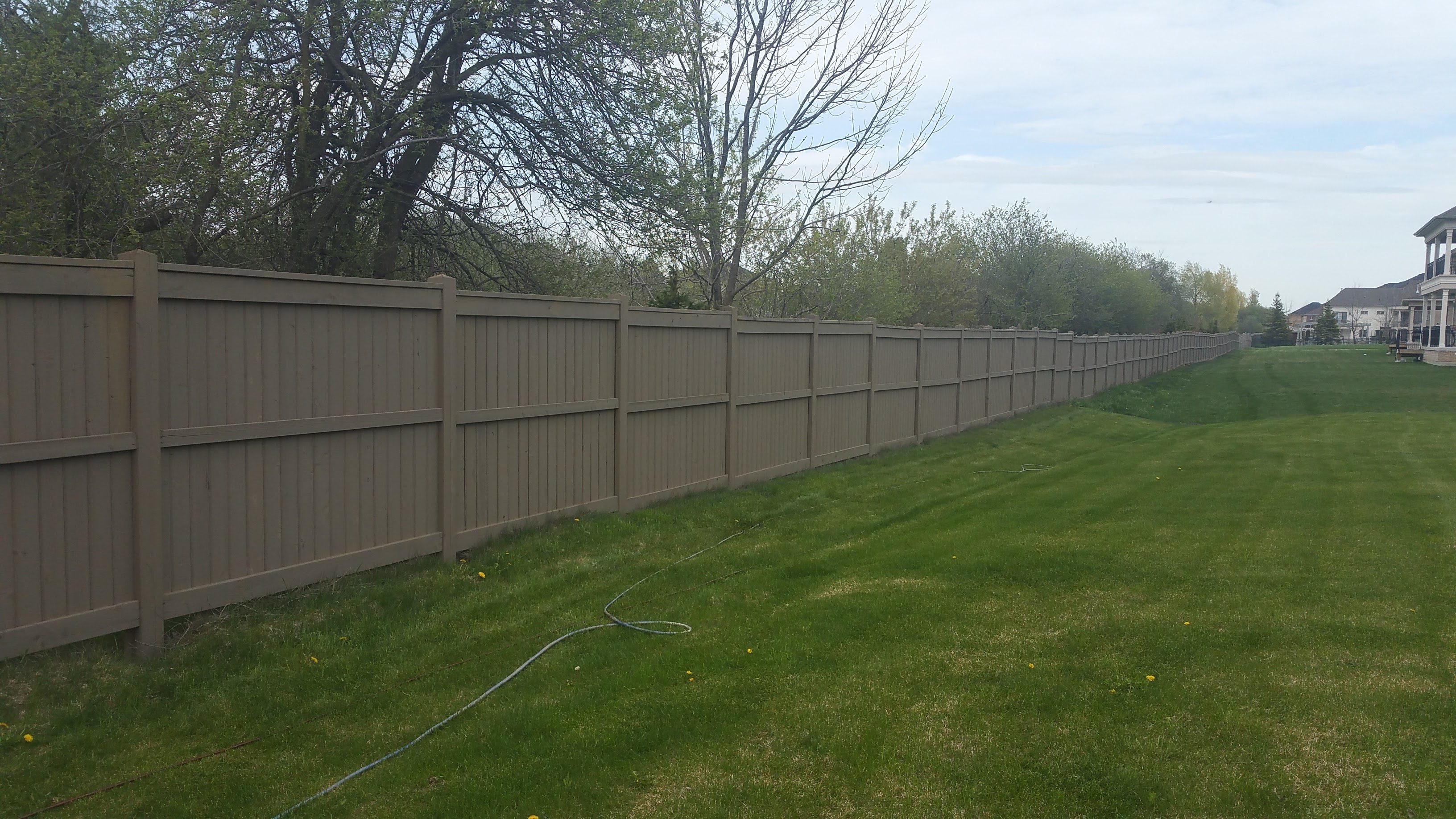 Long beige privacy fence along green lawn
