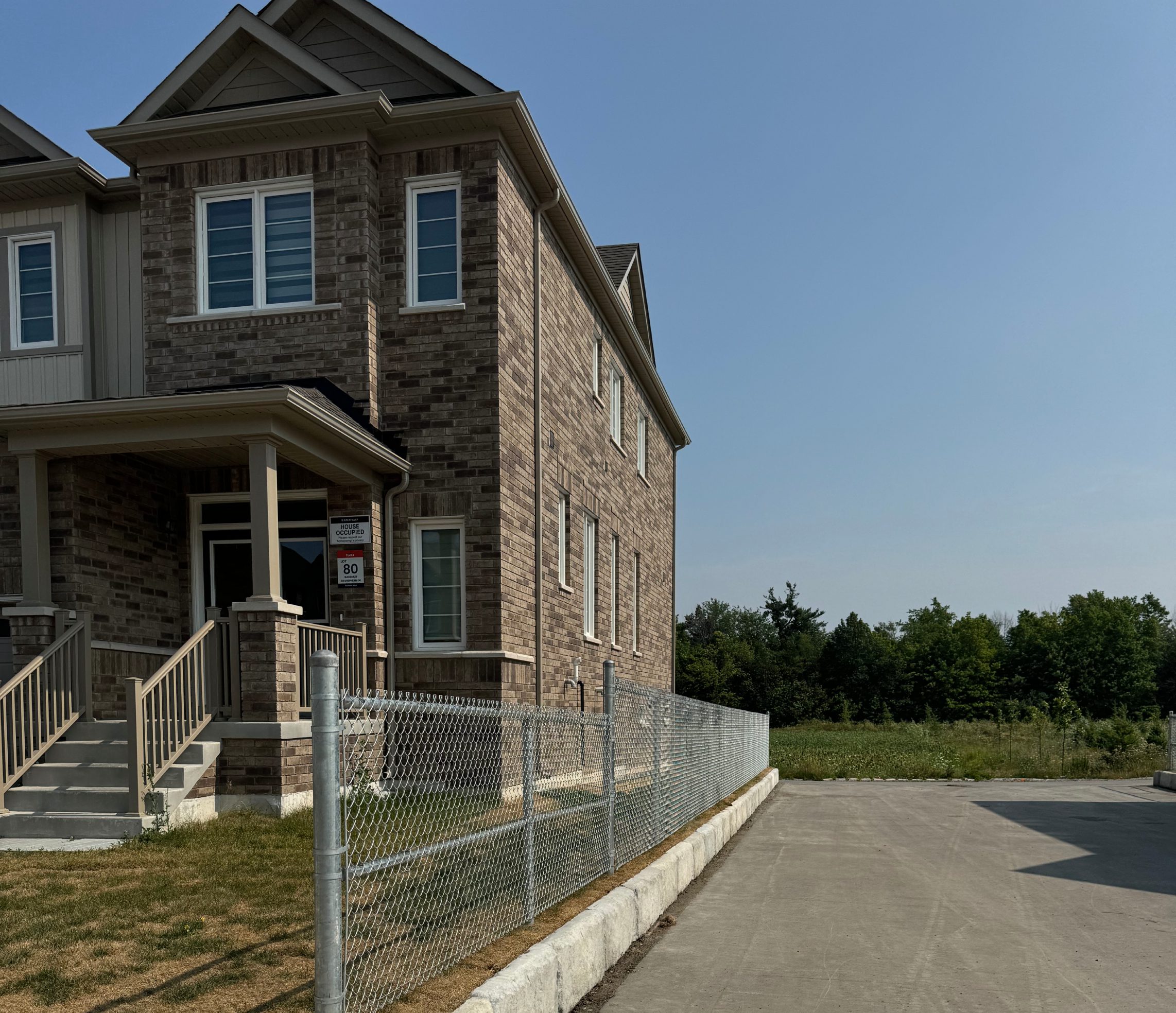 Brick townhouse with chain-link fence and driveway