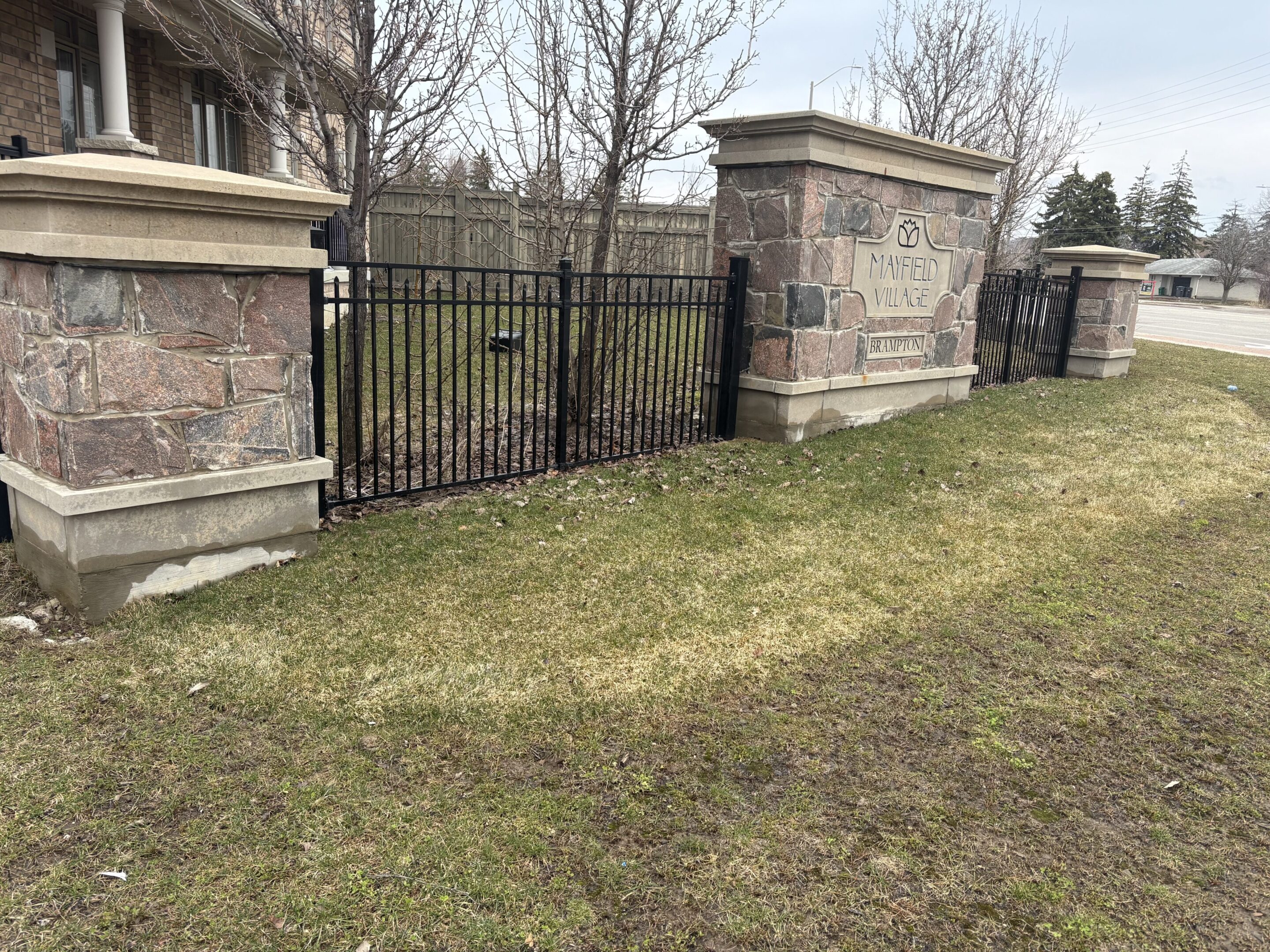 Residential stone pillars and black metal fence