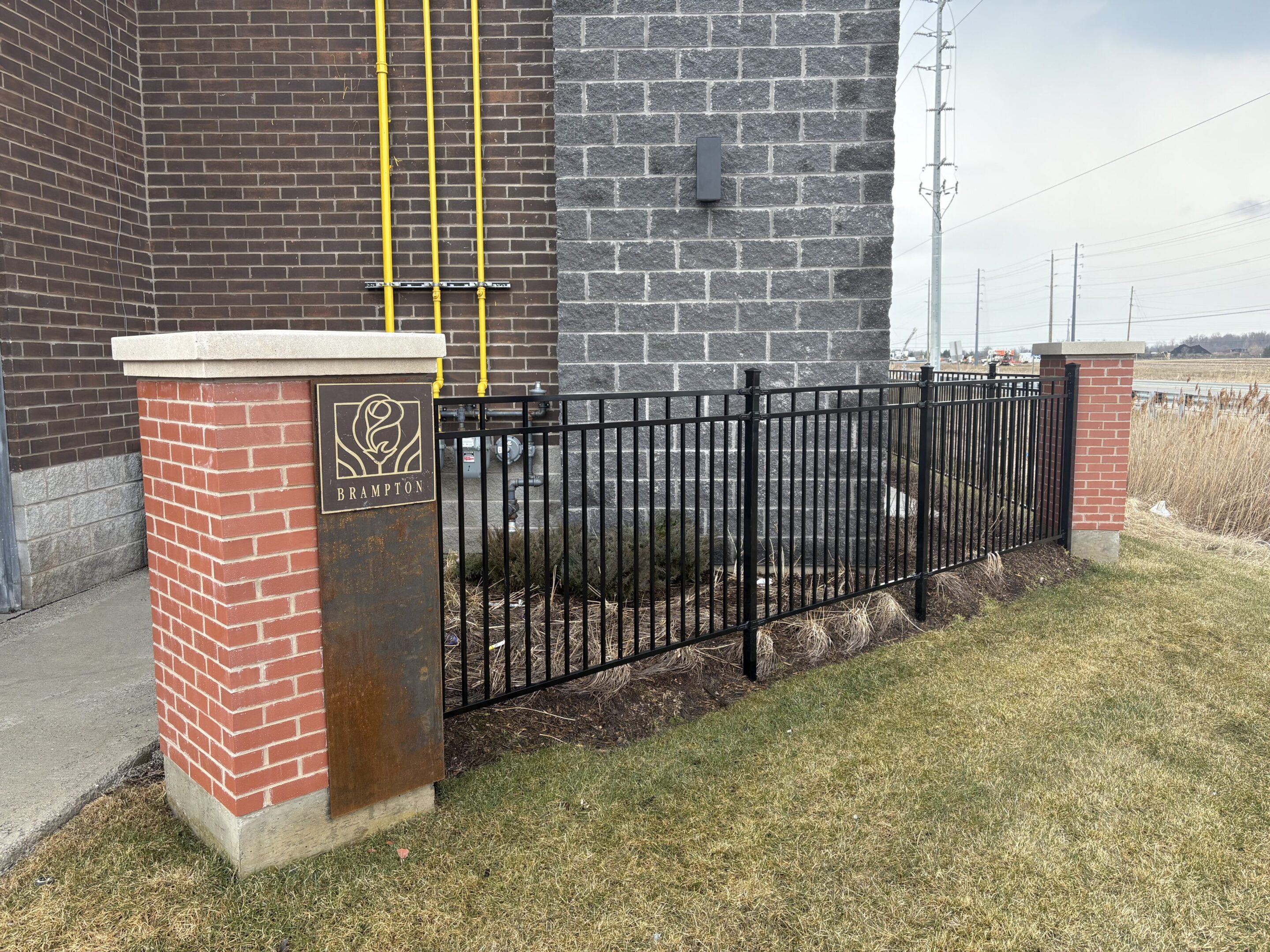 Brick pillar, metal fence at building corner