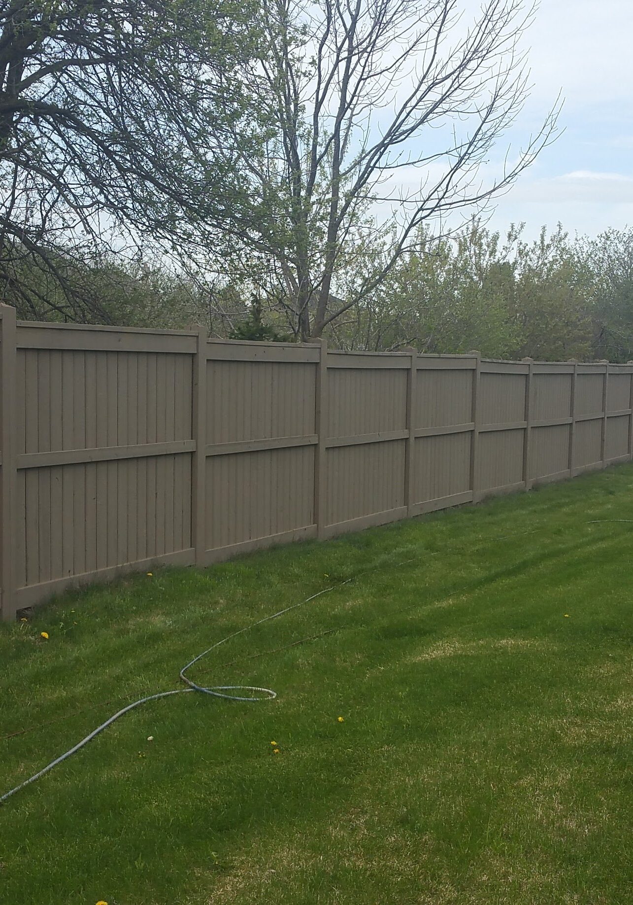 Long beige privacy fence along green lawn